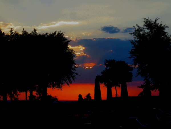 Siluetas de gente guardiola a la puesta de sol en el Paseo del Norte
